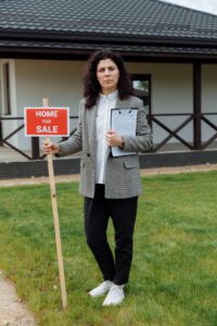 Realtor holding a Home for Sale sign in front of a freshly painted house